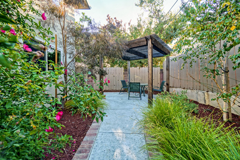 a patio with a table and chairs in a backyard